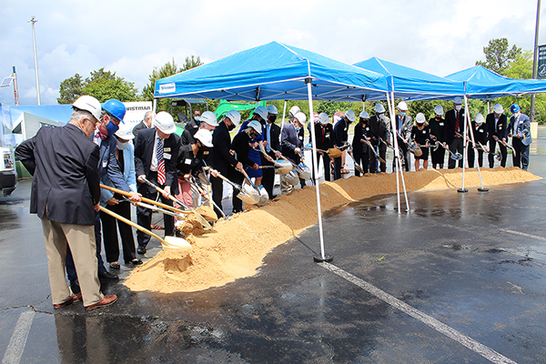 人们戴着安全帽，拿着铁锹，准备在仪式上破土动工